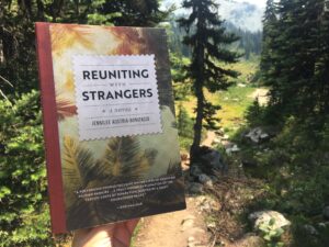 Image shows Reuniting With Strangers book against a background of trees for the book review.